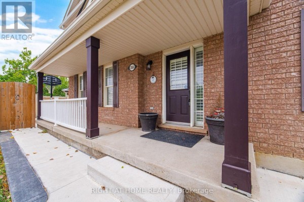 Covered front porch with a white railing, dark brown door, and potted plants. - 355 Brisdale Drive, Brampton