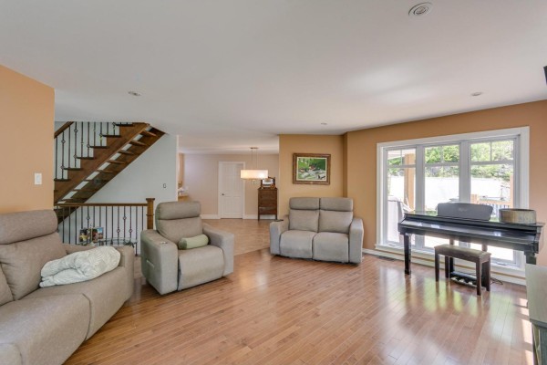 Living room with beige reclining sofas, a grand piano, and a large window overlooking the outdoors. - 355 Ch. St-antoine, Val Des Monts