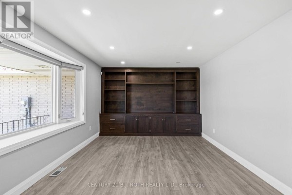 Room with large dark wood built-in entertainment unit and a wide window. - 355 Mapleview Drive W, Barrie
