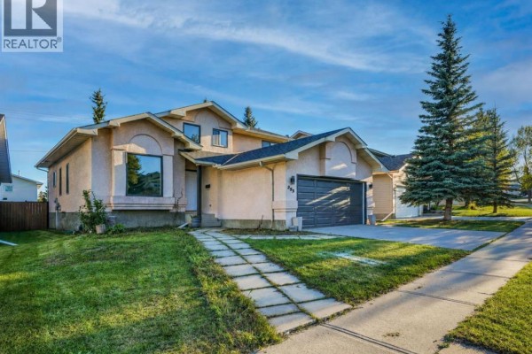 Side view of a stucco house with a large window and concrete walkway. - 355 Millrise Drive Sw, Calgary