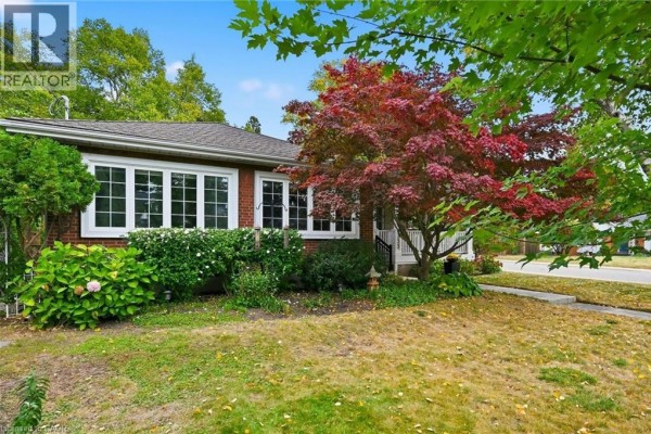 Side exterior view of the brick house with large windows and landscaping. - 355 Newbold Drive, Burlington