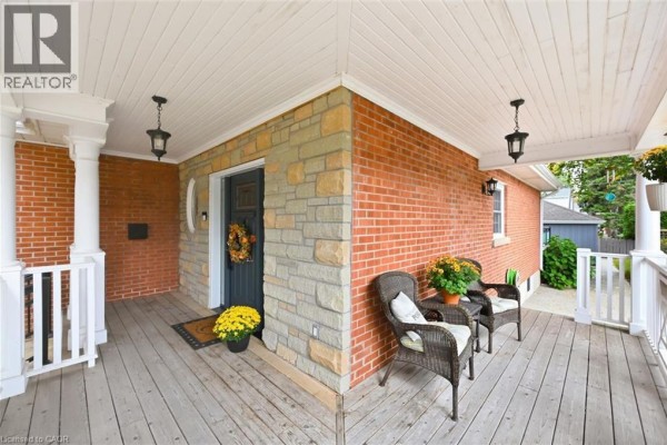 Covered front porch with brick and stone accents, seating, and hanging lights. - 355 Newbold Drive, Burlington