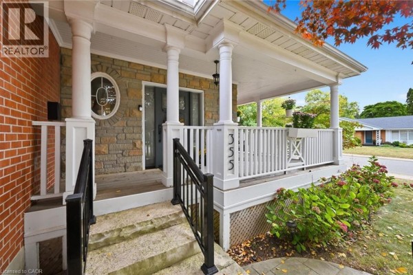 Front porch entrance with stone accents, white railing, and stairs with black handrails. - 355 Newbold Drive, Burlington