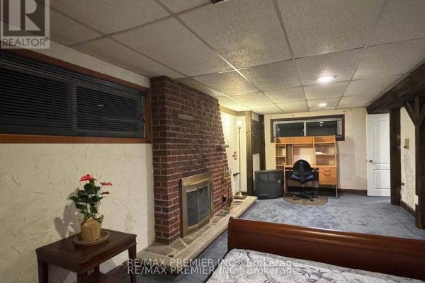 A bedroom with a grey upholstered bed frame, laminate flooring, and wood cabinets. - 3551 Burningelm Crescent, Mississauga