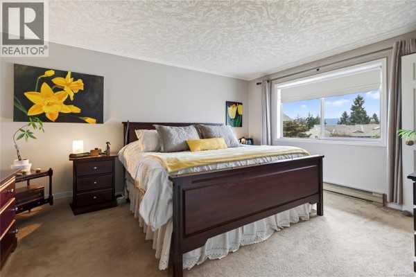 Primary bedroom with king bed, dark wood furniture, carpet, and a large window. - 356 Rees Rd, Courtenay