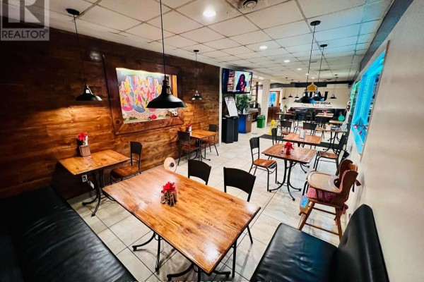 Open dining layout with wooden accents, black chairs, and a view of the Taj Mahal mural - 357 Mill Street, Essa