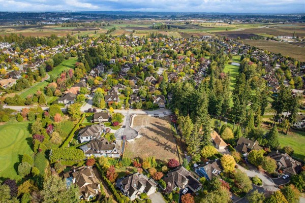 Aerial view of a cul-de-sac with vacant land, surrounded by houses and trees, with a distant view of farmland. - 3578 158 Street, Surrey