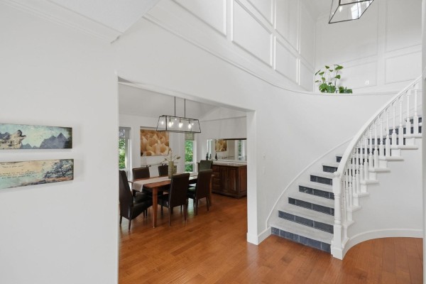 Living room with a fireplace, two armchairs, a coffee table, and a view of the dining area. - 35787 Graystone Drive, Abbotsford