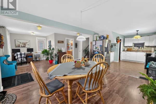 Open concept living, dining, and kitchen area with wood laminate flooring and white cabinets. - 358 Ogden Avenue, Timmins