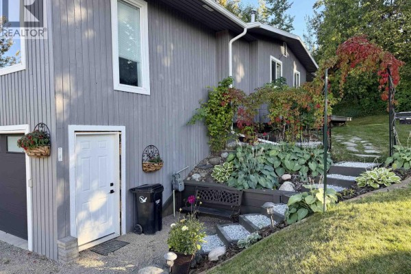 Laundry room with white washer and dryer, storage shelves, and a doorway to another room. - 358 W 5th Street, Vanderhoof