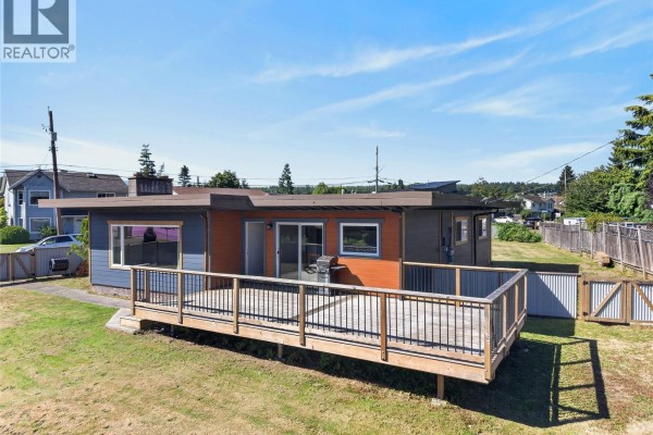 Aerial view of the wooden deck attached to the ranch house, overlooking a green lawn and backyard. - 3584 Island Hwy, Campbell River