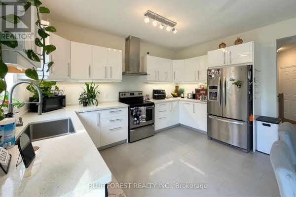 Modern kitchen with white high-gloss cabinets, stainless steel appliances, and quartz countertops. - 3584 Singleton Avenue, London South