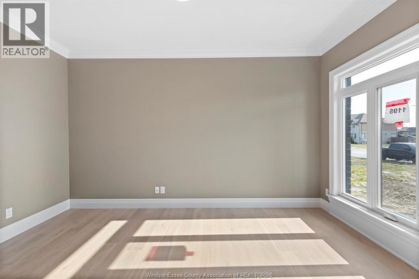 Empty room with light brown walls, a large window, and light wood flooring, showing sunlight streaming in. - 3586 Sutton Avenue, Windsor