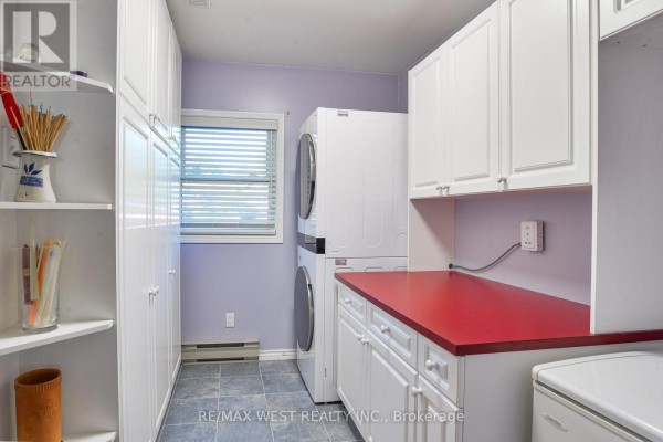 Laundry room with white cabinets, red countertop, stacked washer/dryer - 3587 Lauderdale Point Crescent Severn