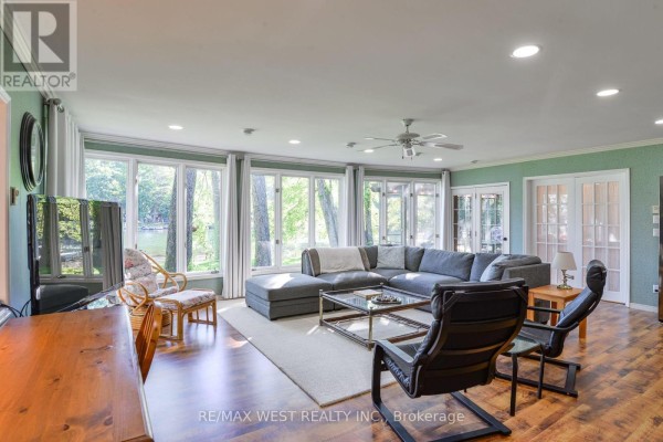 Spacious living room with a large grey sectional, floor-to-ceiling windows, and water view. - 3587 Lauderdale Point Crescent, Severn