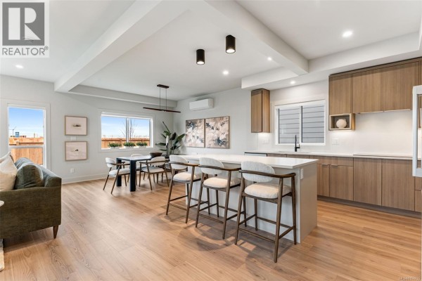 Kitchen island with bar stools, dining table, and modern artwork on the wall. - 3587 Temperate Pl, Colwood
