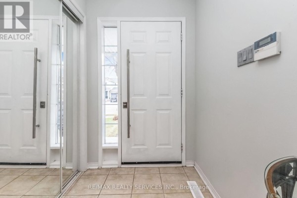 Interior view of a home entryway with a white front door, large mirrored closet doors, and tiled flooring. - 359 Edenbrook Hill Drive, Brampton