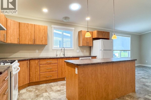Kitchen with light wood cabinets, granite countertops, and a large white refrigerator. - 3591 Old Vernon Road Unit# 110b, Kelowna