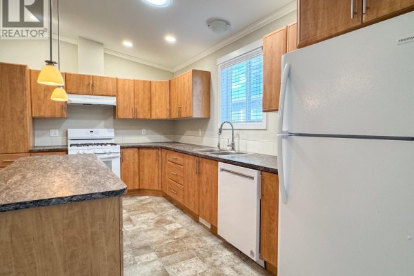 View of the kitchen with light wood cabinets, white appliances, and a large island. - 3591 Old Vernon Road Unit# 110b, Kelowna
