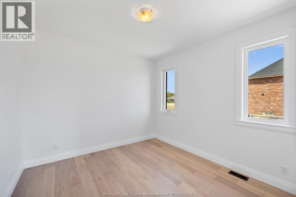 Empty bedroom with white walls, wood floors, and two vertical windows. - 3592 Sutton Avenue, Windsor