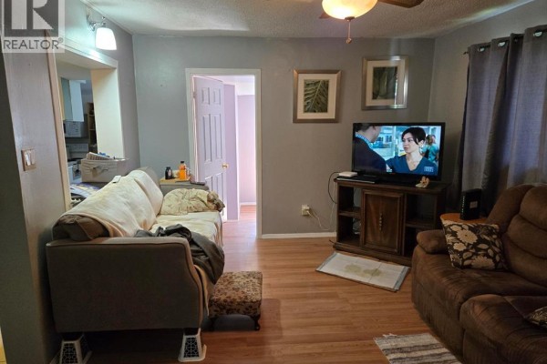 Living room with two sofas, a TV on a stand, and a doorway to another room. - 3595 Queen, Windsor