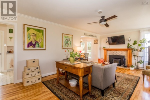 Living room with hardwood floors, fireplace, sofa, and paintings on the wall. - 3596 Clementsvale Road, Clementsvale