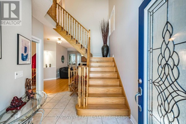 Interior foyer with a staircase, tile flooring, and wood railings. - 3598 Fountain Park Avenue, Mississauga