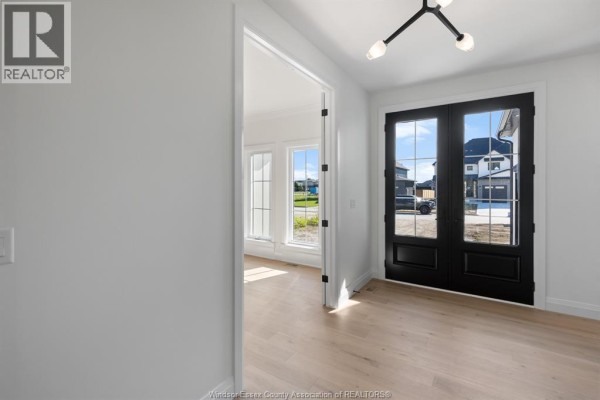 Empty foyer with white walls, light wood floors, and black double doors. - 3598 Sutton Avenue, Windsor