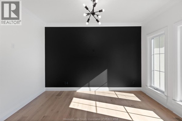Empty dining room with white walls, black accent wall, and light wood floors. - 3598 Sutton Avenue, Windsor