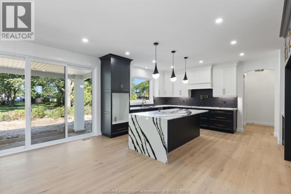 Open concept kitchen with white cabinets, dark cabinets, and a black and white island. - 3598 Sutton Avenue, Windsor
