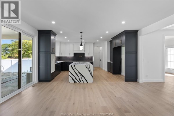 Open concept kitchen with white cabinets, dark cabinets, island, and patio doors. - 3598 Sutton Avenue, Windsor