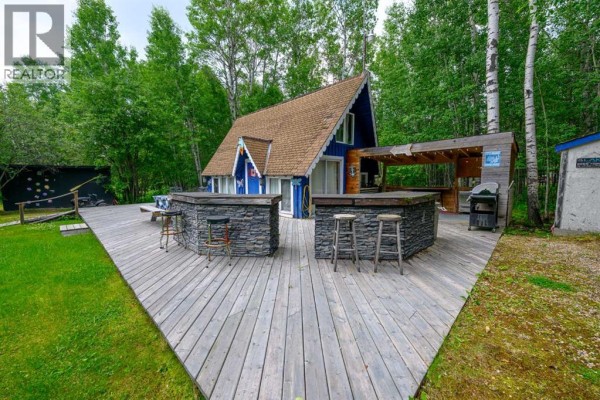 Wide view of the deck, outdoor bar with stools, and the blue A-frame cabin. - 36, 70544 243 Range, Rural Greenview No  16, M D  Of