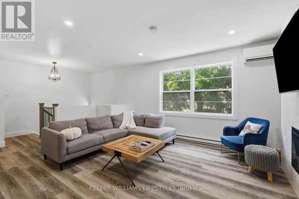 Living room with large window, grey sectional sofa, blue accent chair, and wood plank flooring. - 36 - 105 Andover Drive, London South