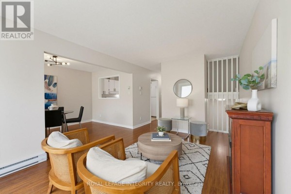Living room with fireplace, two chairs, rug, dining area, and hallway. - 36 - 3415 Uplands Drive, Ottawa