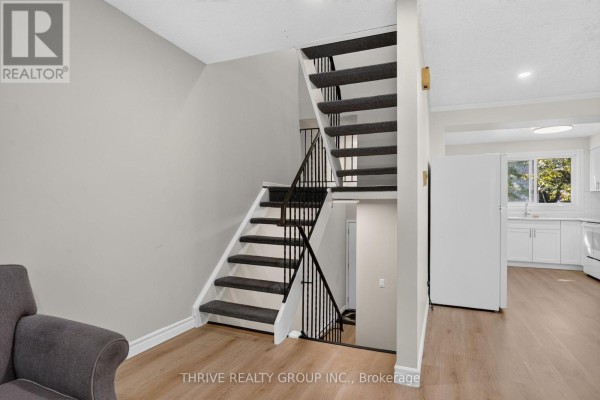 Staircase with dark gray carpeted treads and white risers with black metal railings. - 36 - 40 Summit Avenue, London North