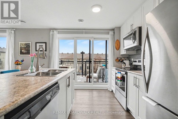 A kitchen with white cabinets, stainless steel appliances, and a large island. - 36 - 454 Via Verona Street, Ottawa
