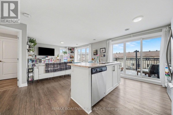 An open-concept living area with a kitchen island, sofa, and balcony access. - 36 - 454 Via Verona Street, Ottawa