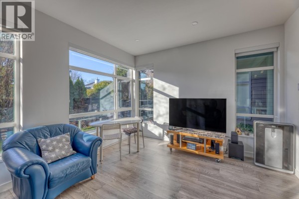 Living room with blue armchair, tables, television, and large windows. - 36 10511 No. 5 Road, Richmond
