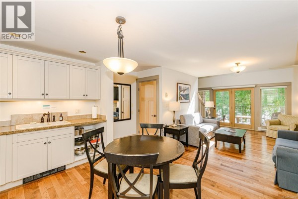 Open-concept living and dining area with kitchen, round table, and sofa. - 36 315 Robinson Rd, Salt Spring