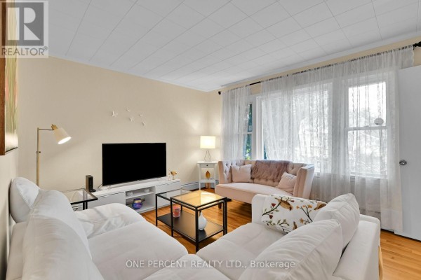 Living room with white sofas, a pink tufted sofa, and large windows. - 36 Argue Drive, Ottawa