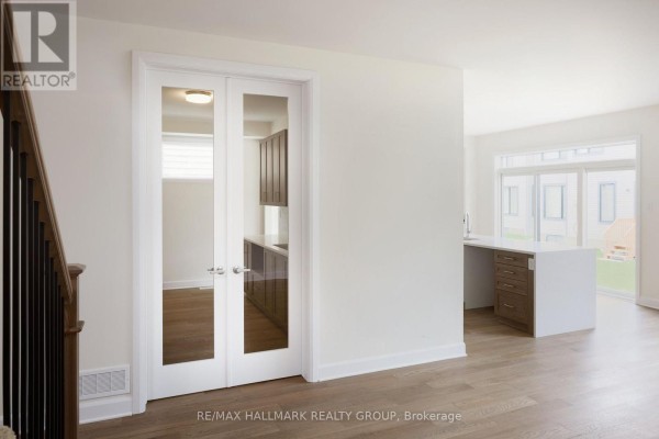 View through glass doors into a pantry with dark cabinetry and a modern kitchen island. - 36 Big Dipper Street, Ottawa