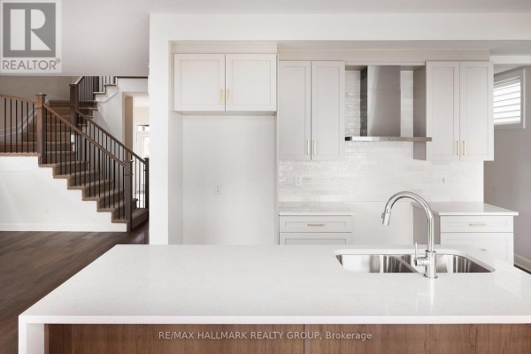 Close-up of a white kitchen island with sink and faucet, overlooking the staircase. - 36 Big Dipper Street, Ottawa