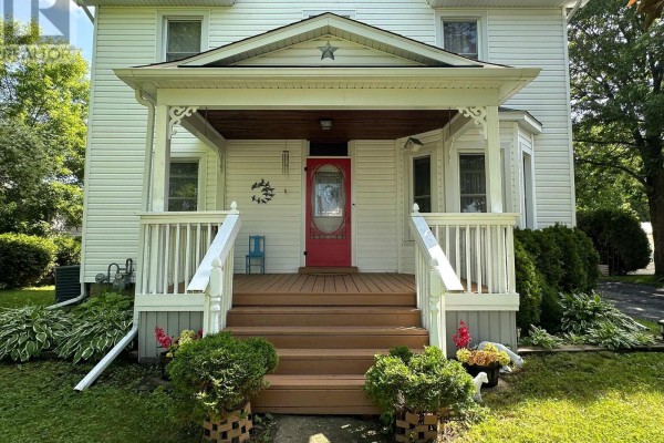 Close-up of the covered front porch with a red door and white railings. - 36 Brouse Drive E, South Dundas