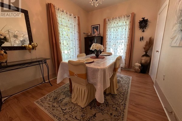 Dining room with wood floors, a table covered in a white tablecloth, and sheer curtains. - 36 Brouse Drive E, South Dundas