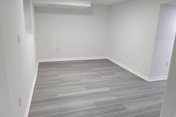Empty room with gray laminate flooring and small window - 36 Crombie Street, Clarington