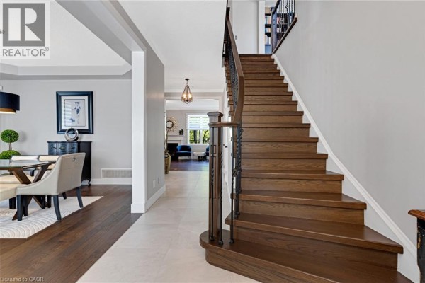 Interior view of the foyer with dark wood stairs, light tile flooring, and an open-concept layout. - 36 Dellgrove Circle, Cambridge