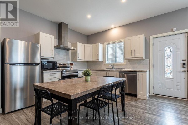 Kitchen with white cabinets, stainless steel appliances, and a dining table. - 36 Division Street, St  Catharines