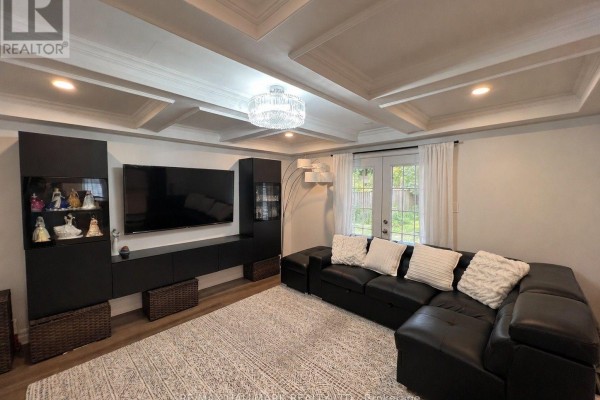 Living room with black sectional sofa, large TV entertainment unit, coffered ceiling, and glass doors. - 36 Fergus Avenue N, Richmond Hill