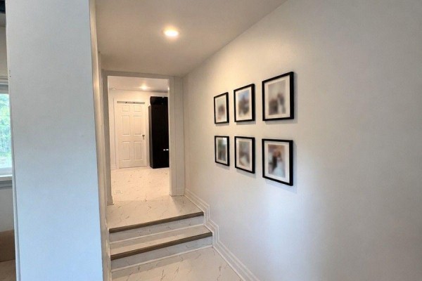Hallway with white walls, framed photos on the wall, and steps leading down to a bright room. - 36 Fergus Avenue N, Richmond Hill