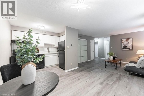 Open concept kitchen and living area with white cabinets, black appliances, and grey flooring. - 36 James Street S Unit# 303, Hamilton